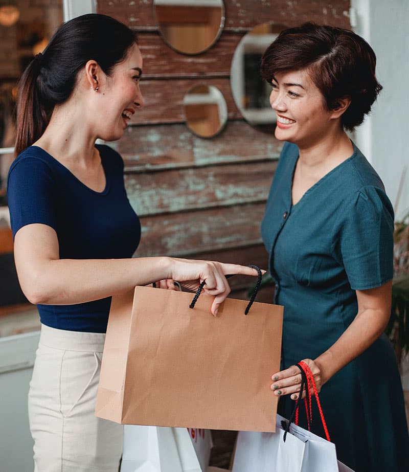 A store salesperson laughing together with a customer who just made a purchase.