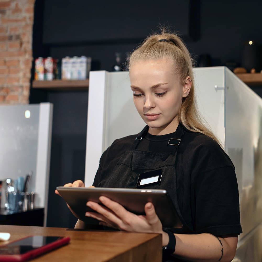 A young employee in a store or restaurant chain reviewing important information on a tablet.